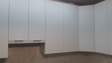 Обработаны и установлены белые панели для кухонных шкафов. Все элементы подогнаны, обеспечивая плавное открытие и закрытие. Завершено аккуратно, с учётом всех размеров и углов.