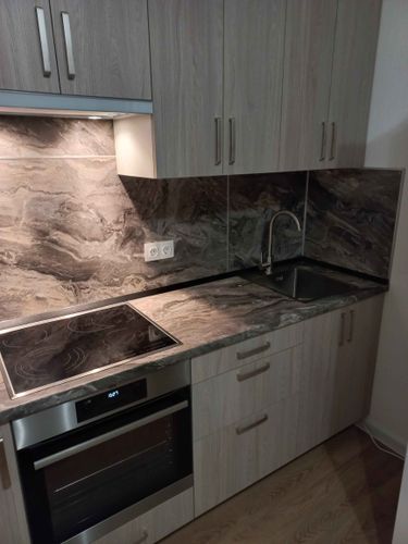 Установлены шкафы, закреплена столешница, вмонтирована варочная панель, подключена мойка, оформлен фартук. Все элементы собраны и установлены, завершив монтаж кухни.