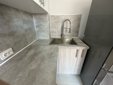 Установлены шкафы, смонтирована столешница, врезана мойка, подключен смеситель, закреплены фасады, выполнена подгонка панелей, подключены розетки, завершена отделка стен.