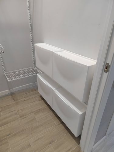 Установлены белые настенные ящики в два ряда на светлой стене. Полки закреплены ровно, обеспечивая надежное хранение. Завершенный монтаж гармонично вписывается в интерьер помещения.