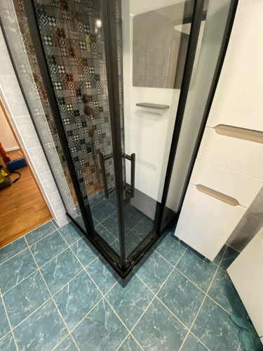 Установлена новая душевая кабина с прозрачными дверями, выполнена укладка плитки на полу и стенах, добавлены полки для удобства, обеспечена герметичность и функциональность конструкции.