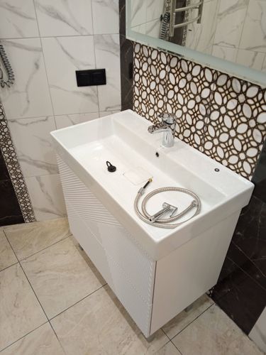 Завершена установка зеркала в ванной комнате над раковиной. Зеркало надежно закреплено на стене, обеспечивая устойчивость и безопасность. Интерьер выглядит современно и стильно.