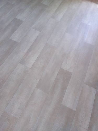 На полу ровно уложено покрытие, без видимых швов и пузырей. Материал аккуратно подогнан, обеспечивая гладкую и эстетичную поверхность, создающую уютную атмосферу в помещении.