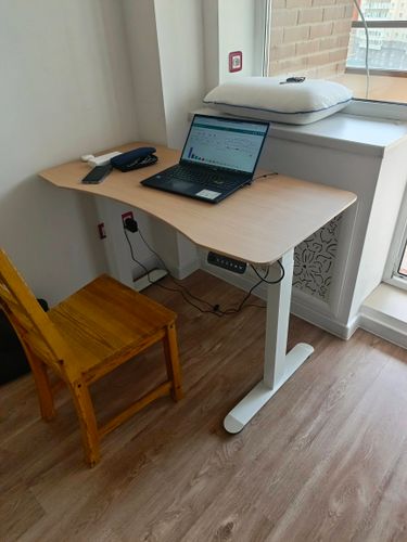 Собран новый стол: установлены ножки, закреплена столешница, подключены провода. Рабочая поверхность готова к использованию, организовано пространство для работы с ноутбуком.