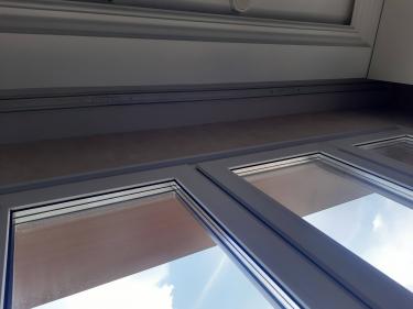 Закреплен профиль на потолке, обеспечивая надежную фиксацию для штор. Установлены крепежи, выровнены по уровню, обеспечивая эстетичный вид и функциональность.