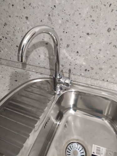 Установлена кухонная мойка из нержавеющей стали с современным смесителем на фоне стильного фартука из искусственного камня. Завершена сборка и монтаж всех элементов.