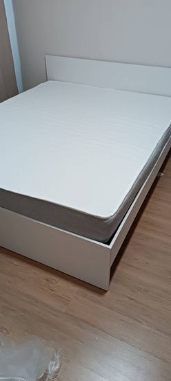 Собрана двуспальная кровать: установлены каркас, изголовье, закреплены боковые панели, уложен матрас. Все элементы надежно соединены, конструкция устойчива и готова к использованию.