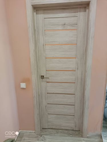 Изображение демонстрирует установленную складную дверь в интерьере. Конструкция закреплена в проеме, оснащена ручкой и петлями. Завершена отделка, обеспечивающая плавное функционирование.