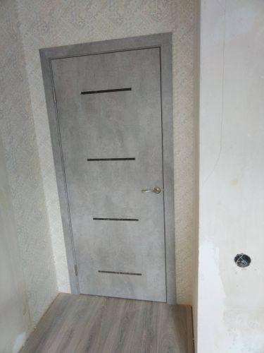 Установлена новая межкомнатная дверь с серым покрытием, аккуратно закреплена в проеме, добавлены петли и ручка. Полностью завершена работа по монтажу, обеспечена плавная работа.