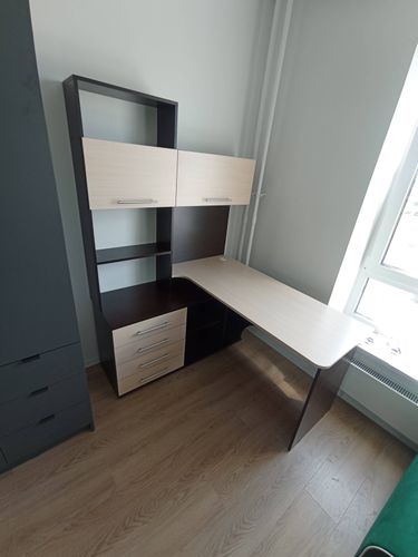 Собран угловой стол с полками и ящиками. Установлены дверцы, закреплены ручки. Все элементы надежно соединены, конструкция устойчива. Завершенная работа готова к использованию.