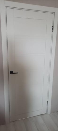 Установлена белая межкомнатная дверь с черной ручкой. Проведены работы по монтажу полотна, коробки, петель и фурнитуры. Дверь аккуратно вписана в проем, обеспечена плавная работа.