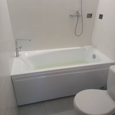 Изображение ванной комнаты с установленной новой сантехникой: ванна, смеситель и душ. Все элементы блестят чистотой, создавая современный и аккуратный вид.