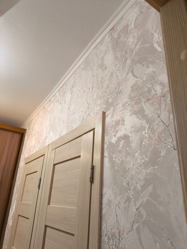 На стене аккуратно наклеены фотообои с нежным узором. Поверхность ровная, без видимых стыков и пузырей. Рисунок гармонично сочетается с интерьером, создавая уютную атмосферу.