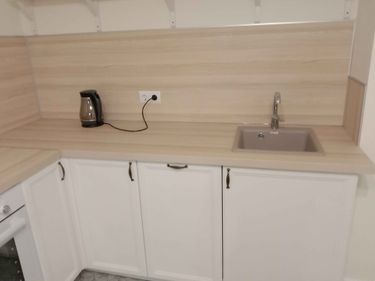 Установлены шкафы, закреплена столешница, вмонтирована мойка, подключен смеситель, размещены полки, подключена техника, выполнена отделка стен панелями.