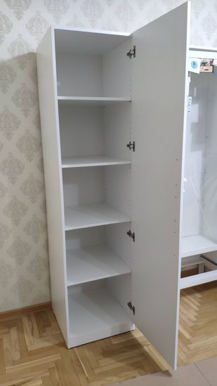 Установлен шкаф с полками, закреплен на стене. Дверцы навешаны, петли отрегулированы. Конструкция устойчива, готова к использованию.