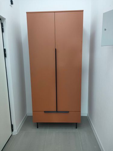 Собран шкаф: установлены дверцы, закреплены полки, прикручены ручки, выровнены ножки, проверена устойчивость, выполнена финишная проверка, обеспечена функциональность, завершена сборка.