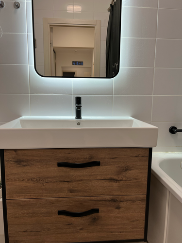 Установлено зеркало с подсветкой над раковиной в ванной комнате. Закреплено на стене, выровнено по уровню. Подключена подсветка для комфортного использования.