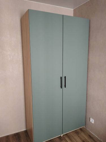 На стене установлен шкаф с дверцами, аккуратно закрепленный и выровненный. Работа выполнена с учетом всех технических требований, обеспечивая надежность и устойчивость конструкции.