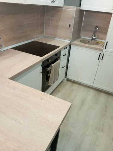 Установлены шкафы, смонтирована столешница, подключена варочная панель и мойка, закреплены фасады, выполнена отделка стен панелями. Завершена сборка и настройка всех элементов.