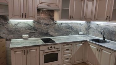 На кухне установлена новая столешница с вырезами под варочную панель и мойку. Поверхность идеально подогнана по размерам, обеспечивая функциональность и эстетичный вид.