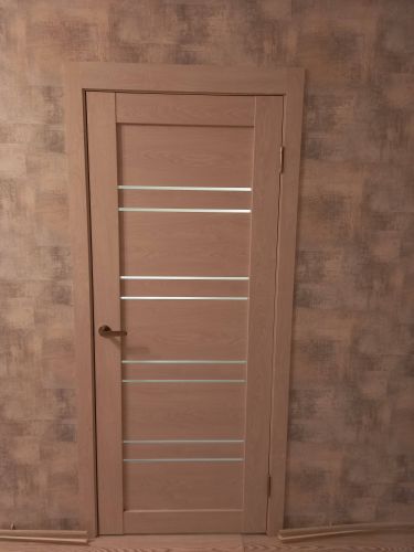 Изображена установленная складная дверь, закрепленная в проеме. Полотно ровно размещено, фурнитура надежно закреплена. Завершены все монтажные работы, обеспечена плавная эксплуатация.