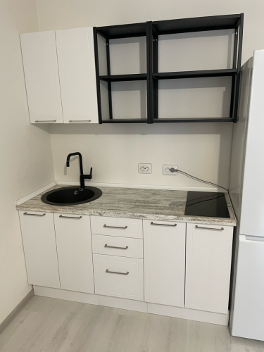 Установлены шкафы, смонтирована столешница, врезана раковина, подключена варочная панель, закреплены ручки, проведены коммуникации, навешены полки, подключены розетки.