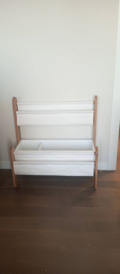 Установлена деревянная полка с белыми тканевыми карманами, надежно закреплена на стене. Полка выровнена, обеспечена устойчивость и безопасность.