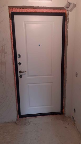 Установлена металлическая дверь, закреплена в проеме, зазоры заполнены монтажной пеной для герметичности, добавлены замки и ручка, обеспечена надежная фиксация конструкции.