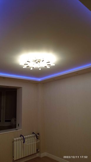 На потолке закреплён светильник, подключённый к электросети. Установлено освещение с декоративной подсветкой, создающей уютную атмосферу в комнате. Завершён монтаж безупречно.