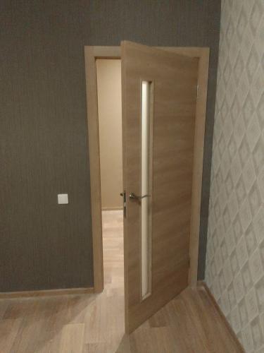 Установлена деревянная створка с ручкой и стеклянной вставкой, закреплена в проеме, отрегулированы петли, обеспечена плавная работа, добавлены наличники для завершенного вида.