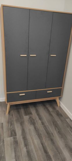 Собран шкаф с тремя дверцами и двумя ящиками, установлены ручки, выровнены ножки, проверена устойчивость конструкции, выполнена финишная отделка, проверена функциональность.