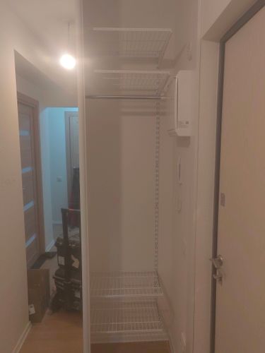 Установлены металлические полки в нише возле двери, обеспечивая дополнительное место для хранения. Конструкция надежно закреплена на стене, создавая удобное решение для организации пространства.