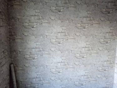 На стенах аккуратно размещены фотообои с изображением кирпичной кладки, создавая эффект текстурированной поверхности. Все стыки ровные, рисунок совпадает, придавая комнате стильный вид.