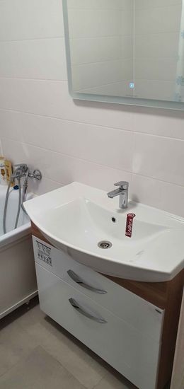 Установлена раковина с подключением смесителя и сифона, выполнена герметизация швов, проверена работа системы водоотведения, закреплен шкафчик под умывальником.