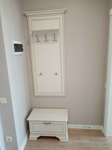 Установлена настенная панель с крючками для одежды и обувница с выдвижным ящиком. Компактная и функциональная мебель создает уютное пространство для хранения вещей в прихожей.