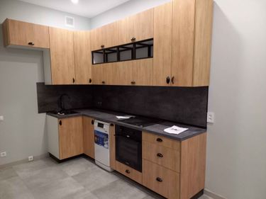 Готовые элементы для кухонного гарнитура были точно вырезаны и установлены. Фасады из дерева гармонично сочетаются с интерьером, обеспечивая функциональность и стильное оформление пространства.