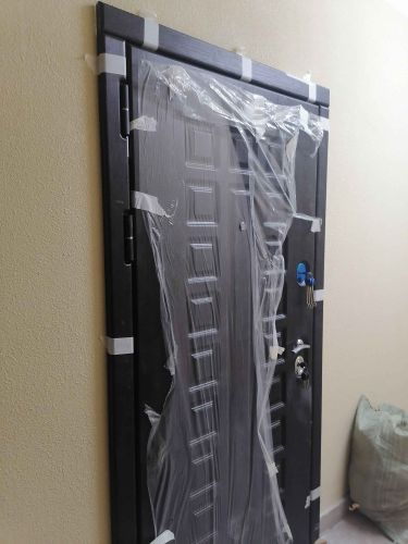 Дверь обшита панелями, установлены наличники, защитная пленка временно оставлена. Работа завершена, поверхность обновлена, улучшен внешний вид, добавлена звукоизоляция.