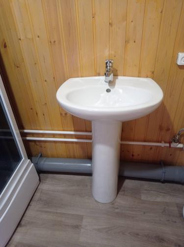 Установлен умывальник с подключением к водопроводу и канализации. Смеситель закреплён, трубы подведены, слив функционирует. Завершена проверка герметичности и работоспособности системы.