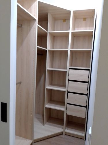 Установлены деревянные полки в угловой нише, обеспечивая функциональное хранение. Конструкция закреплена на стене, выровнена по уровню, обеспечивая надежность и устойчивость.