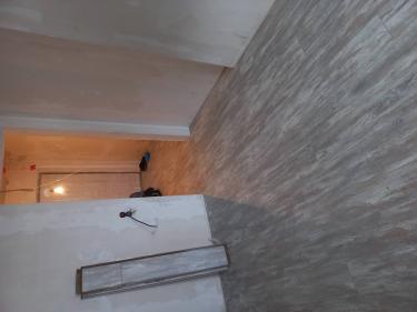 На полу уложено покрытие из ламината, создающее ровную и эстетичную поверхность. Панели плотно соединены, образуя цельное покрытие, гармонично вписывающееся в интерьер комнаты.