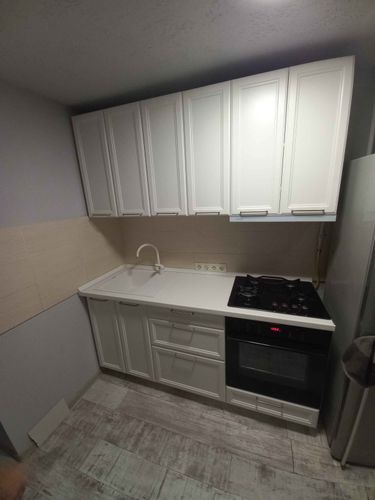 Установлены шкафы, закреплена столешница, подключена мойка, смонтирована варочная панель и духовой шкаф. Все элементы аккуратно выровнены, обеспечена функциональность и эстетика.