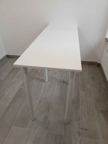Установлена белая столешница из искусственного камня, аккуратно закреплена на металлических опорах, идеально прилегает к стене, создавая современный и стильный вид интерьера.