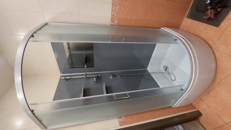 Установлена угловая душевая конструкция с раздвижными дверцами, подключены водопровод и слив, закреплены панели, проверена герметичность соединений, добавлены полки для удобства.