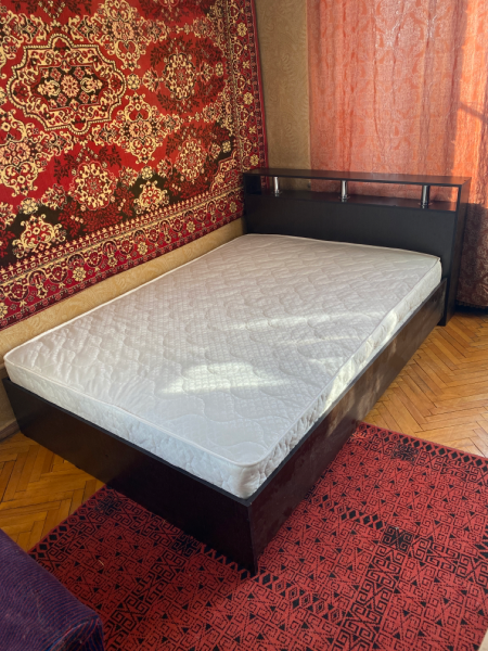 Собрана двуспальная кровать: установлено изголовье, закреплены боковые панели, уложено основание, размещён матрас. Все элементы соединены, конструкция устойчива, готова к использованию.