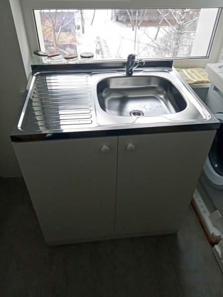 Установлена новая раковина с краном в кухонный шкаф, подключены водопроводные трубы и слив. Все элементы надежно закреплены, обеспечена герметичность соединений.