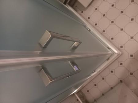Установлена новая душевая кабина с прозрачными дверями и металлическими ручками на месте прежней ванны. Поддон закреплён на плиточном полу, обеспечивая современный вид и функциональность.
