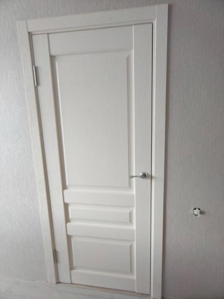 Установлена новая белая дверь, закреплены петли, врезана ручка, отрегулирована коробка, обеспечена плавность открывания, проведена финальная проверка, устранены зазоры, завершена отделка.