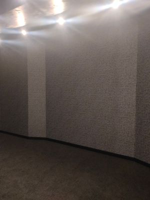 На полу уложены плитки ковролина, создающие ровное покрытие. Завершенная работа обеспечивает комфорт и эстетичность помещения. Светильники на потолке подчеркивают текстуру стен и пола.