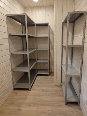 Установлены металлические полки в углу комнаты. Конструкция прочная, устойчивая, идеально вписывается в интерьер. Полки размещены на разной высоте для удобства хранения вещей.