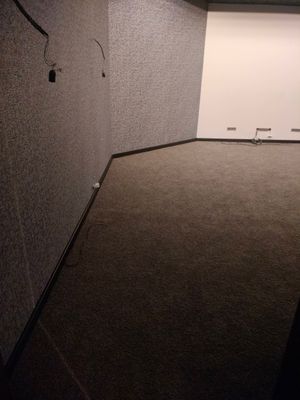 На полу уложены плитки ковролина, создающие ровное покрытие. Все элементы аккуратно подогнаны, швы незаметны. Завершена отделка, обеспечивающая комфорт и эстетичный вид помещения.